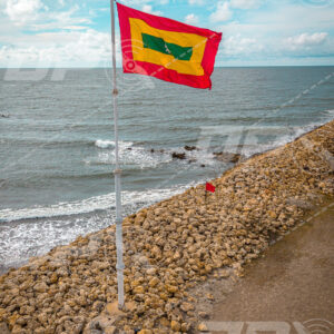 Bandera de Cartagena ondeando frente al mar Caribe sobre escollera costera