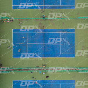 Canchas de tenis vistas desde arriba con jugadores en complejo deportivo urbano
