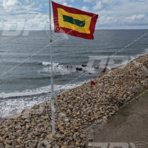 Bandera de Cartagena ondeando frente al mar Caribe sobre escollera costera